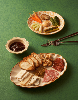 Charcuterie plate with cheese, cured meats, nuts, and pickled vegetables.